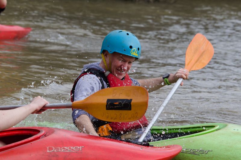 A picture of an adult volunteer getting splashed while kayaking